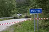 Veiskiltet Flåklypa står ved en sperret vei med rød-hvitt bånd og vegetasjon langs kanten.