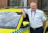 Anders Halden står ved en gul ambulanse med grønn rutemarkering utenfor en bygning.