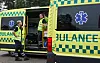 To personer i refleksvester står ved en åpen gulgrønn dansDe ambulanse med blått nød-symbol.