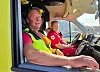 To menn i rød uniform og refleksvest sitter foran i en ambulanse.