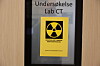 Et skilt på en dør viser teksten «Undersøkelse Lab CT» og et gult strålefare-symbol.