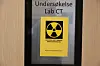 Et skilt på en dør viser teksten «Undersøkelse Lab CT» og et gult strålefare-symbol.