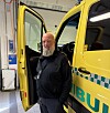 En mann står ved siden av en gul ambulanse med åpne dører inne i et lyst verksted.