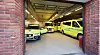 Flere gule og grønne ambulanser står parkert i en opplyst garasje.