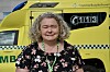 Smilende kvinne står foran en gul ambulanse merket 113 og Finnmarkssykehuset.